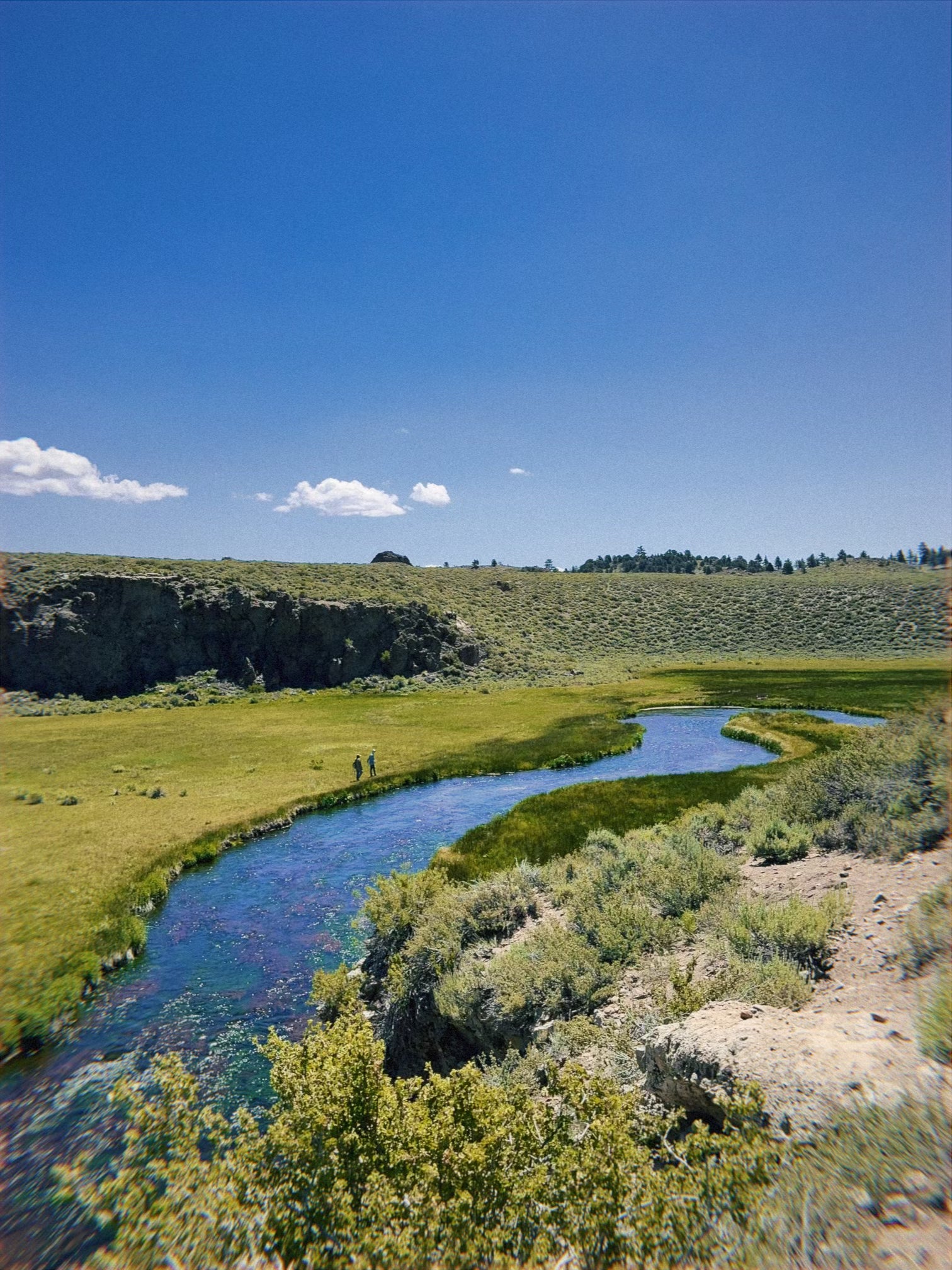 Hot Creek Ranch in California's Eastern Sierra in early June with two fly anglers walking in the distance